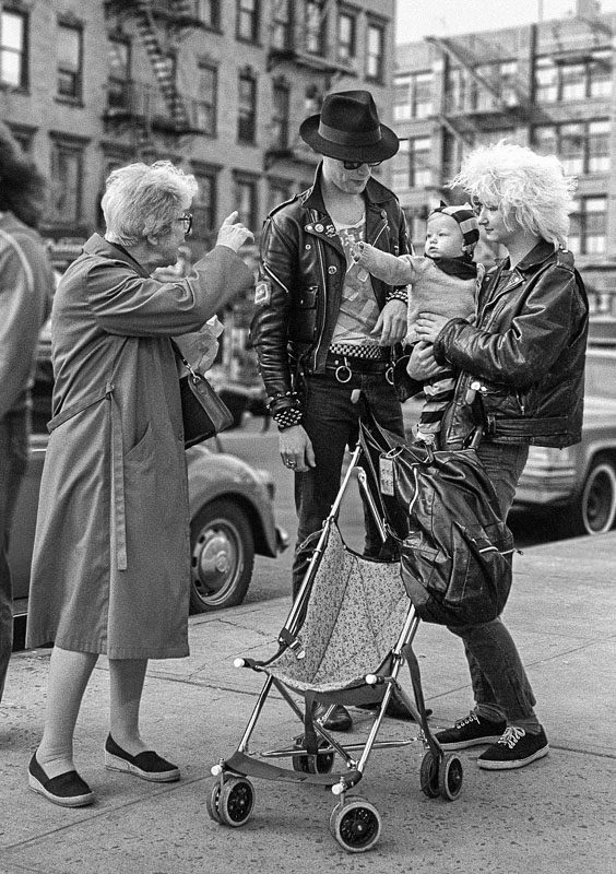 Image shows older conservative woman greeting a Punk couple and their baby on 4th Ave. in NYC. Personal work of North Carolina-based photojournalist Bruce Johnson
